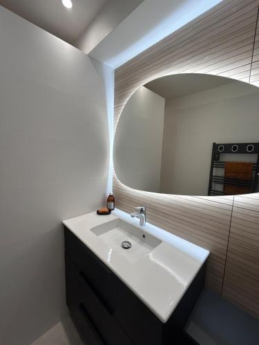 une salle de bain avec un lavabo blanc et un miroir dans l'établissement Un balcon sur la mer - Mer & sable fin, à Plérin