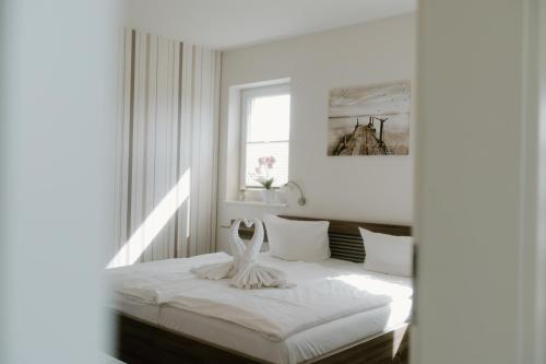 a white bedroom with a bed with a window at Villa Große Freiheit in Trent