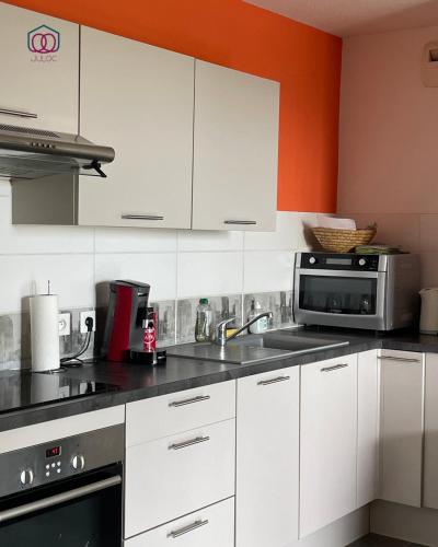 une cuisine avec des armoires blanches et un micro-ondes dans l'établissement Sérénité - Logement calme au coeur de Strasbourg, à Strasbourg