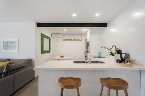 a kitchen and living room with a sink and two stools at El Rincón House Tenerife Tijoco in Adeje