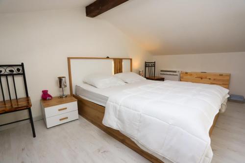 - une chambre avec un grand lit blanc et une table de nuit dans l'établissement Petite maison sympa dans résidence avec piscine, à Saint-Cyprien