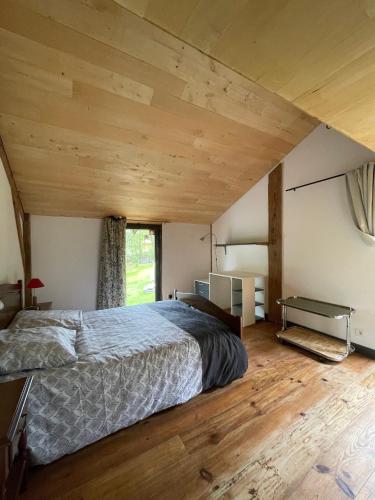 une chambre avec un grand lit avec un plafond en bois dans l'établissement Maison Bois, à Sergeac