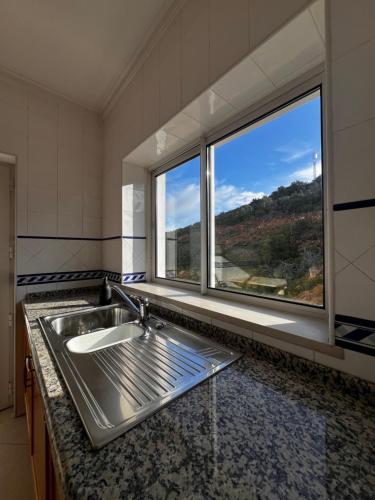 a kitchen with a sink and a large window at Ilumina Hostel Albufeira in Albufeira