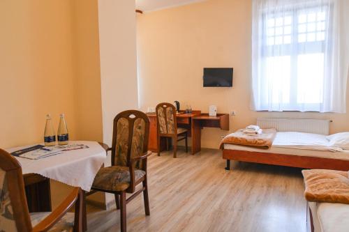a room with two beds and a table and a desk at Willa Dąbrówka in Szczawno-Zdrój