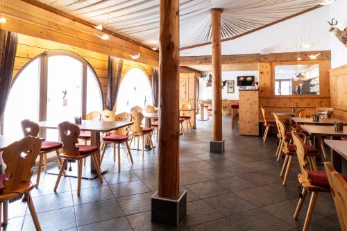 a restaurant with wooden walls and tables and chairs at Hotel Chesa Grischa in Sils Maria