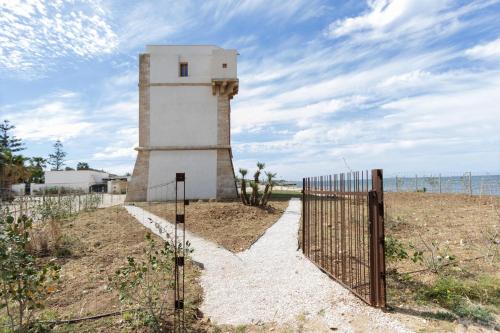 Un faro en medio de un campo con una valla en Visitsicilia Torre Marausa, en Marausa