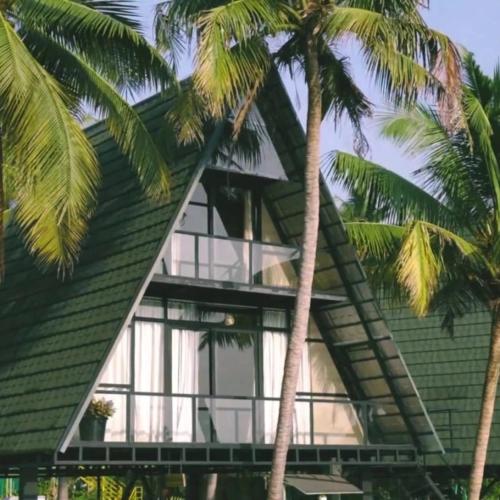 a green house with palm trees in front of it at Parlak in Karuvapadna