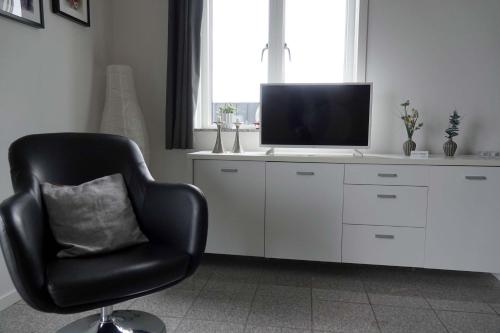 a living room with a chair and a television at Bogense Feriebo in Bogense