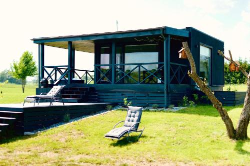 une maison bleue avec deux chaises dans l'herbe dans l'établissement DeerHouse, à Kaliakiemiai