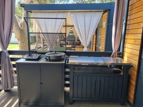an outdoor kitchen with a grill on a patio at Sand & Relax Privlaka - Mobile home "Lavanda" in Privlaka