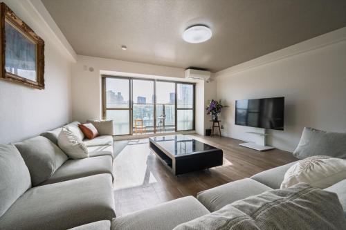 a living room with a couch and a tv at LIT広島駅前 広島駅から徒歩5分 全室リバービューでベッドはairweaveを採用 Spacious rooms with river views all to yourself Supported in Ōsukachō