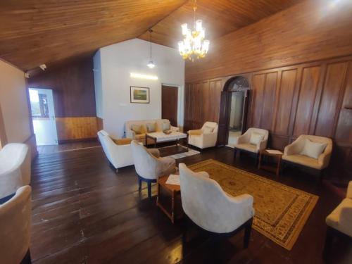 a living room with white furniture and a chandelier at Maharanee Bungalow Darjeeling in Darjeeling