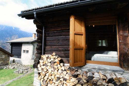 a log cabin with a pile of fire wood outside at Romantic Chalet in the Leventina Mountains by Quokka 360 - Romantic Chalet in Faido