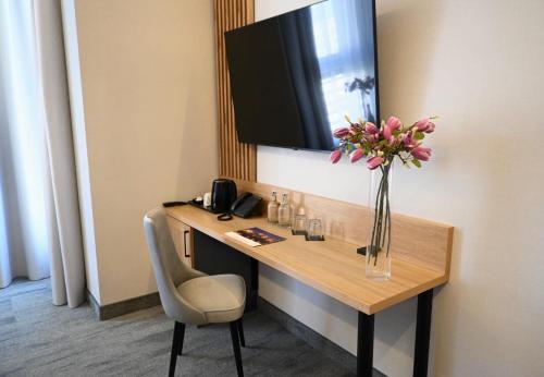 a hotel room with a desk with a vase of flowers at Hotel Centrum Malbork in Malbork