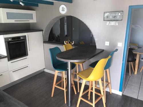 une cuisine avec une table et des chaises jaunes et bleues dans l'établissement Charming House in Normandy, à Gonfreville-l'Orcher