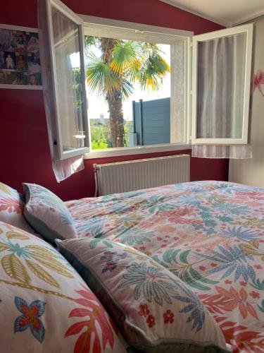 - une chambre avec un lit et une fenêtre avec un palmier dans l'établissement Charming House in Normandy, à Gonfreville-l'Orcher