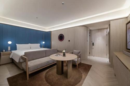 a bedroom with a bed and a couch and a table at Crystal Orange Hotel Shanghai Chongming Nanmen in Shanghai