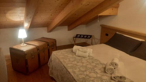 a bedroom with a bed and a suitcase and a lamp at CAMPO BASE CADORE MONOLOCALE MANSARDA con park auto e garage moto in Valle di Cadore