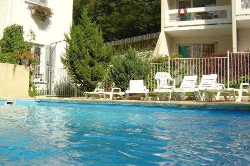 - une piscine avec des chaises blanches dans l'établissement L'Ame du chalet, à Allevard