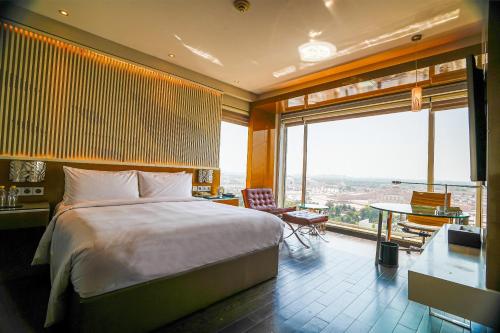 勒克瑙Renaissance Lucknow Hotel, Gomti Nagar的一间带大床和大窗户的卧室