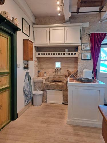 a kitchen with white cabinets and a stone wall at "Les Tournesols" piscine, campagne, idéal familles in Sauveterre