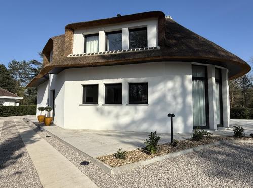 une maison blanche avec un toit de chaume dans l'établissement Villa Les Marais, à Le Touquet-Paris-Plage