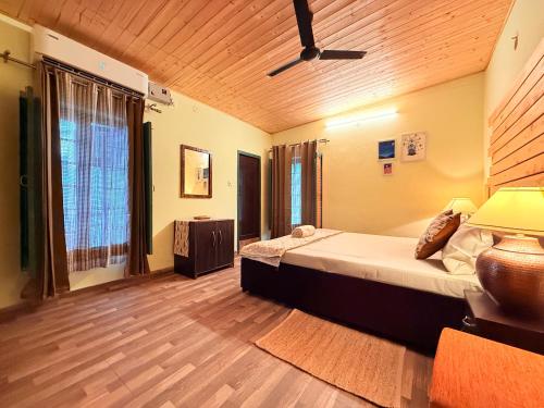 a bedroom with a large bed and a wooden ceiling at Frogs BNB Aviator's Bungalow in Dharmsala