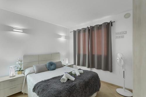 a white bedroom with a bed with two towels on it at Sunset Arguineguin in Arguineguín