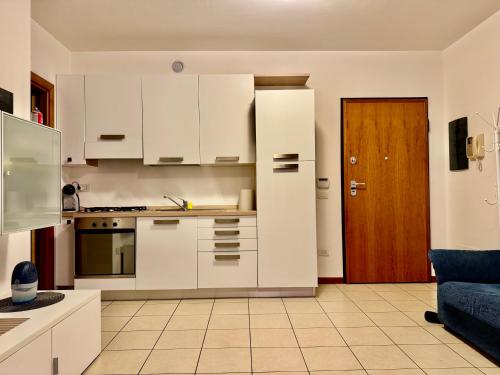 cocina con armarios blancos y sofá azul en Central apartaments, en Bérgamo