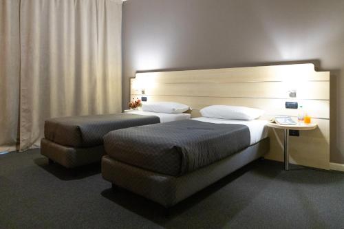a hotel room with two beds and a headboard at Hotel Giallo in Noceto