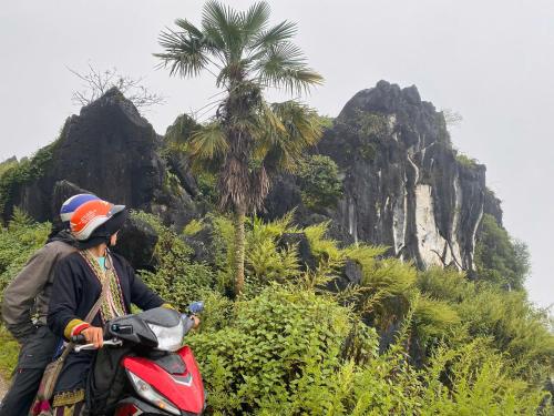 a man riding a scooter in front of a mountain at maison Rose & Jardinier eco homestay in Sa Pa