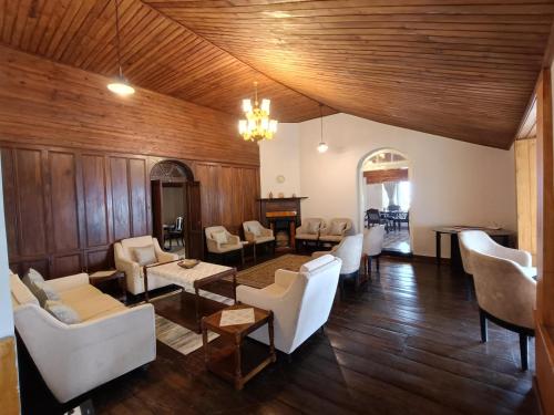 a living room with wooden walls and white furniture at Maharanee Bungalow Darjeeling in Darjeeling