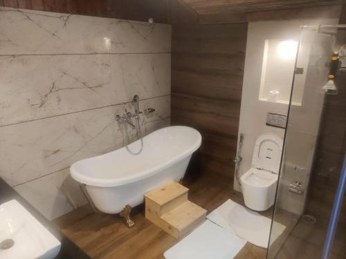 a bathroom with a bath tub and a toilet at Maharanee Bungalow Darjeeling in Darjeeling