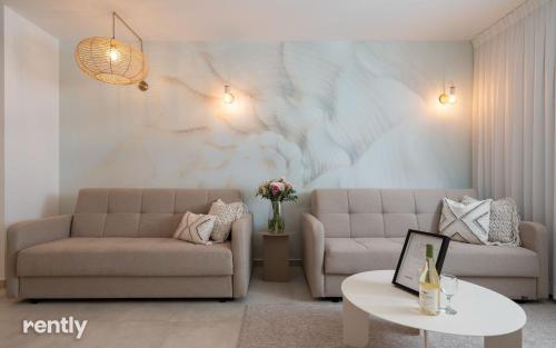 a living room with two couches and a table at Luxury Apartments And Studios At Sea Side By Rently in Eilat