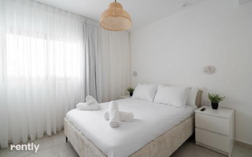 a white bedroom with a bed with towels on it at Luxury Apartments And Studios At Sea Side By Rently in Eilat