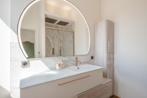 une salle de bain blanche avec un lavabo et un miroir dans l'établissement Mas de l' écluse, à Maussane-les-Alpilles