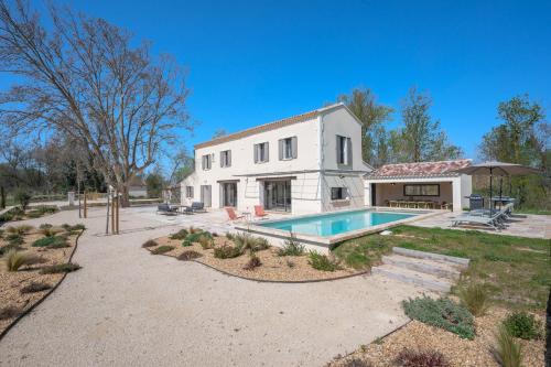 une grande maison blanche avec une piscine devant dans l'établissement Mas de l' écluse, à Maussane-les-Alpilles