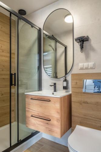 a bathroom with a shower and a sink with a mirror at NT Holiday Apartament in Dźwirzyno
