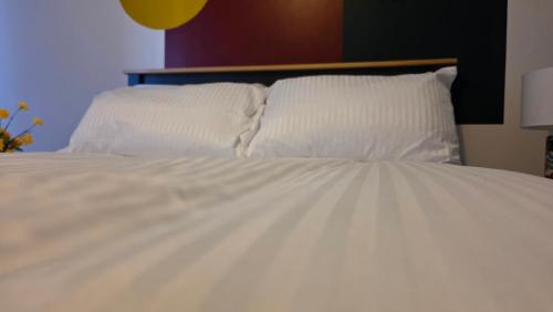 a white bed with two pillows on it at The Ansi9 in Livingston