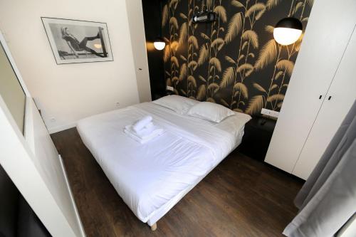 Ce petit lit se trouve dans une chambre dotée d'un papier peint noir et blanc. dans l'établissement Appartement Paris 13 universite - 4P RDC, à Paris