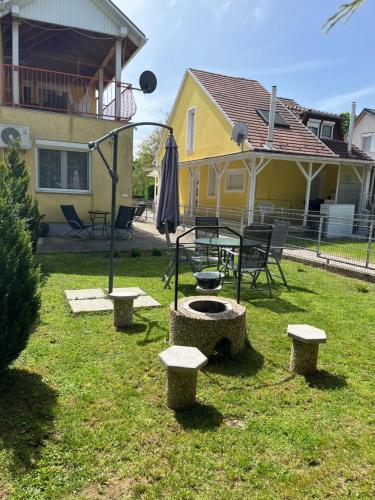 a backyard with a table and benches and an umbrella at Réka Apartmanház in Bük