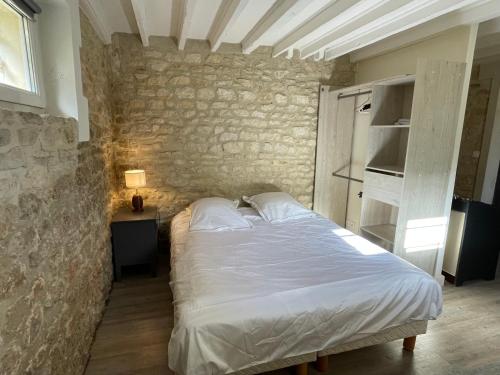 une chambre avec un lit blanc et un mur en pierre dans l'établissement Appartement à 2 pas de la mer et du casino, à Cabourg