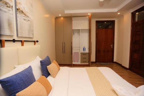 a bedroom with a large white bed with blue pillows at Yunia Luxury 1-Bed Apartment in Busia