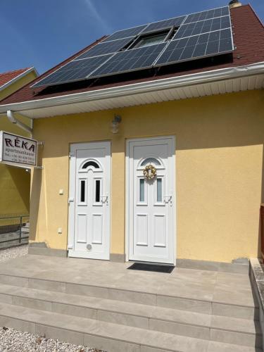 a house with two white doors and a lot of solar panels at Réka Apartmanház in Bük
