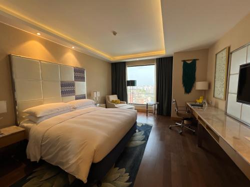 a large bedroom with a large bed and a desk at Renaissance Dhaka Gulshan Hotel in Dhaka