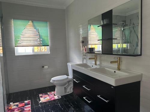 a bathroom with a sink and a toilet and a mirror at Yoga Dreams Negril in Negril