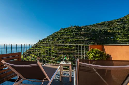 a patio with a chair and a table and a hill at Luxury Seaview Apartments Manarola by Arbaspàa in Manarola
