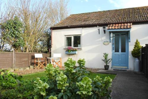 a small white house with a blue door at Cosy Cottage in Rural Lympsham in Lympsham