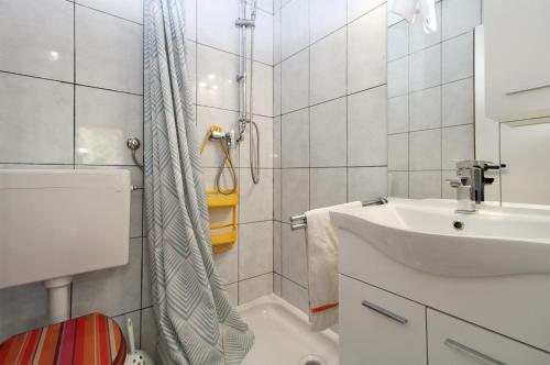 a white bathroom with a sink and a shower at Apartments and rooms Milan 2380 in Barbariga