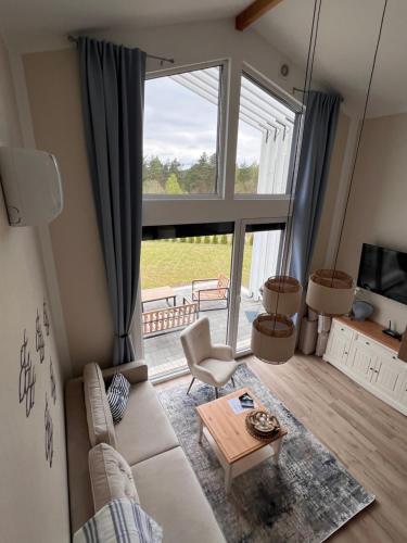 a living room with a couch and a large window at Casa Kashubia - Nowoczesny dom wakacyjny nad jeziorem - Cisza natura i komfort in Brzeźno Szlacheckie